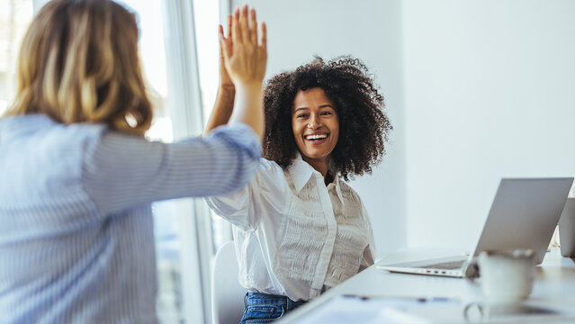 Two Women Sharing a High Five During a Business Meeting in an Office Setting