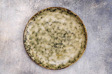 Off-white plate with dark grey spots on light grey background