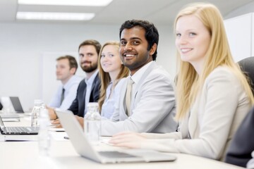 Obraz premium Corporate Meeting Scene Five professionals in formal attire discussing around a table with laptops and water glasses