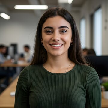 Una joven hispana segura de s&iacute; misma y con una sonrisa amistosa, llena de compa&ntilde;eros de escritorio.