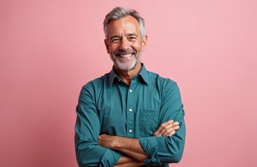 Middle age caucasian man isolated on pink background with arms crossed. Mature male poses, confidently smiles, looks forward. Happy bearded person in green shirt on salmon backdrop. Studio shot.