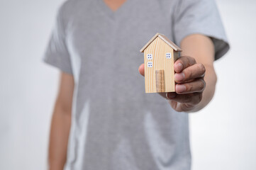Hand Holding Wooden Model House Symbolizing Real Estate Investment