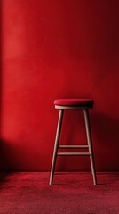 Empty red stool against a bold red wall and carpet in a minimalist interior setting