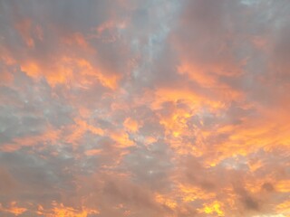 Morning Sunrise - Orange Clouds; Grey Clouds colored orange and yellow by the rising sun, against a pale blue sky.