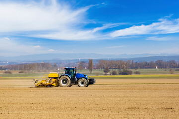Obraz premium Tractor in a field of the early spring time agricultural activities.