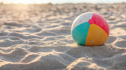 Obraz premium Vibrant Beach Ball Bouncing on Soft Sand Dunes at Sunrise