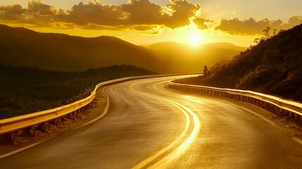 Naklejka premium A winding road curves through a mountainous landscape at sunset. Warm golden light illuminates the asphalt and surrounding hills. 