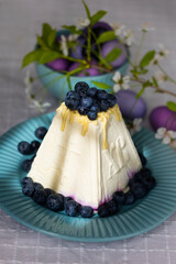 Holiday laid table for Easter with Russian traditional dish called Easter made of cottage cheese, painted eggs in shades of lilac and purple with green blooming branch