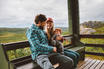 Family lifestyle father and mother with infant baby sitting on terrace traveling in Norway, parents with child happy candid emotions bonding together