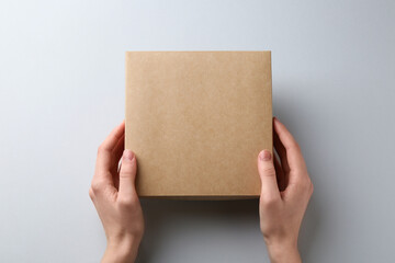 Woman with blank cardboard box on white background, top view. Mockup for design