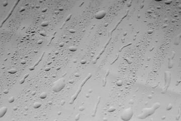 Water drops on grey glass surface, closeup