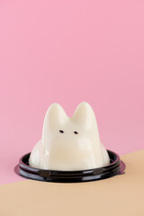 Jiggly cat panna cotta dessert on pink and beige background. Dancing jelly animal mousse. Popular...
