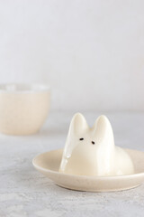 Vanilla jiggly cat dessert in a plate with cup of tea on a gray table. Dancing jelly animal mousse...