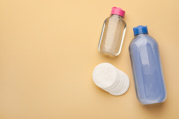 Clean cotton pads and micellar water on beige background, flat lay. Space for text