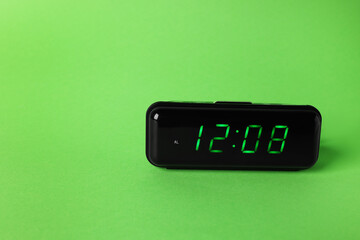 Digital alarm clock showing 12:08 o'clock on green background, space for text