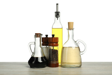 Salad dressings and spices on wooden table against white background