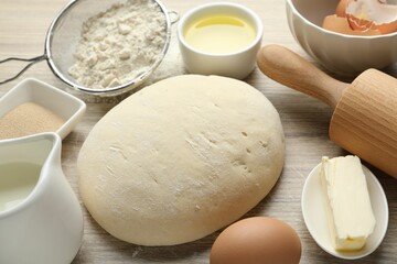 Rolling pin and different ingredients on light wooden table, closeup