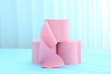 Pink toilet paper rolls on light blue background