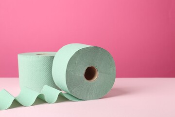 Green toilet paper rolls on pink background. Space for text