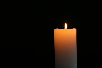 One burning candle on black background, closeup. Space for text