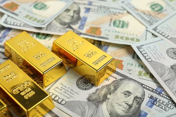 Shiny gold bars on dollar banknotes, closeup. Space for text