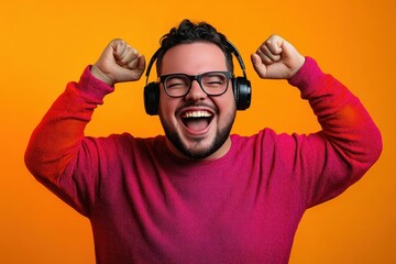 Fototapeta premium Cheerful man enjoying music with headphones on orange background