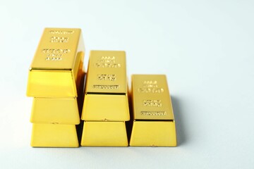 Shiny gold bars on light background, closeup. Space for text