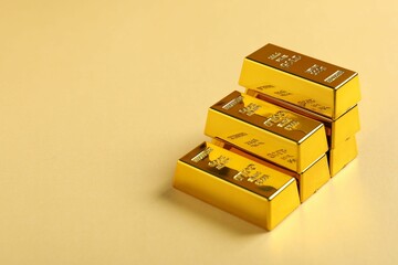 Shiny gold bars on beige background, closeup. Space for text