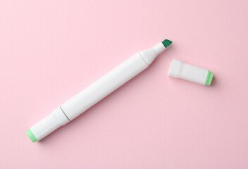 One green double sided marker on pink background, top view