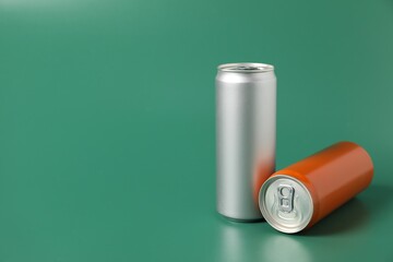 Two aluminium cans of beverage on green background, space for text