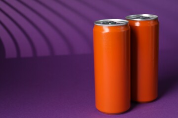 Two tin cans on purple background with shadow, closeup. Space for text