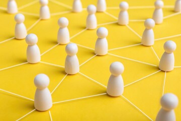 Fototapeta premium Leadership strengthens employee engagement and workplace connection concept. Conceptual illustration of social connections with white figures on a yellow background.