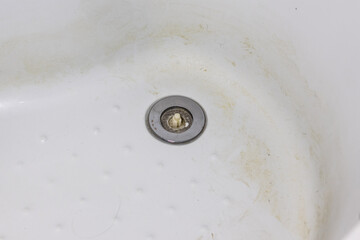 The shower sink is clogged with hair. Close up.