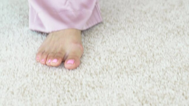 bare female feet walk on the beige Interior pile carpet.
