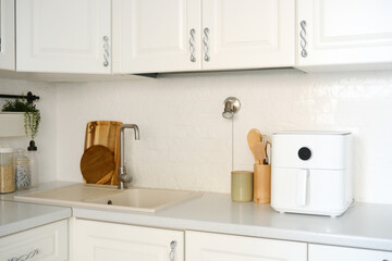 An elegant kitchen space featuring a stylish white air fryer, with clean lines and a beautifully minimalist decor.