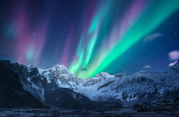 Northern lights over the snowy mountains at night in Lofoten, Norway. Aurora borealis above the...