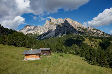 Obraz premium Majestic Dolomites landscape with a rustic cabin near Seceda, showcasing green fields and towering mountains