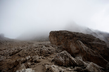 Dramatic skies and mist envelop the Sassolungo mountain in Dolomieten, creating a captivating atmosphere for hikers and nature enthusiasts