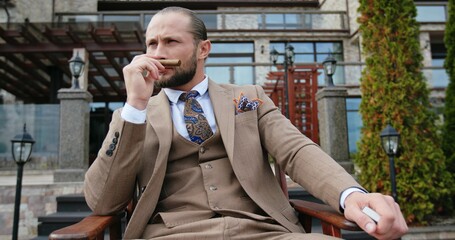 A Sophisticated Man Dressed in a Beige Suit is Pictured as He Relaxes Outdoors Gracefully