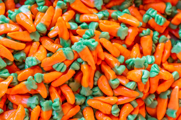 Volumetric background of jelly candies shaped like carrots vibrant orange and green tones create a textured surface
