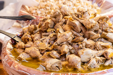 Heap of marinated artichoke hearts soaked in golden oil tender pieces infused with herbs and spices