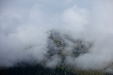 Cloud-covered mountains in Gerlos and Königsleiten, Austria evoke a sense of tranquility and mystery during a misty day