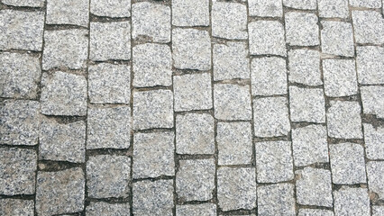 Detailed view of cobblestone pavement showcasing various shades and textures in an urban location during daylight.