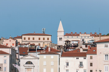 panoramic view of the old town in Piran , with church spires and red-roofed buildings against a clear blue sky