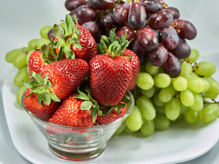 strawberries and grapes clustered on plate
