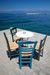 Wooden chairs and table on waterside greek taverna, Koroni, Messenia, Peloponnese, Greece, Europe