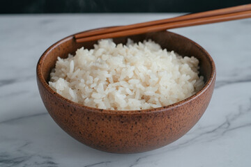 A bowl of white rice with chopsticks in it