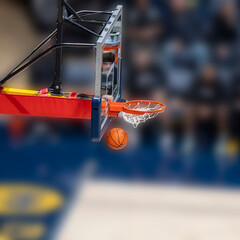 a dynamic basketball moment where the ball is passing through the hoop and net, indicating a successful shot. The hoop and backboard are sharply defined © dfriend150