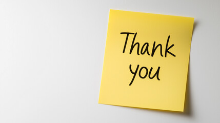 A bright yellow sticky note with Thank you written on it, symbolizing appreciation and gratitude in a minimalistic setting