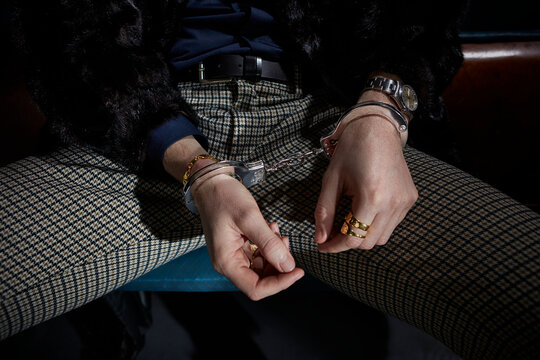 Un homme en &eacute;tat d'arrestation judiciaire qui a les mains menott&eacute;s. La personne pr&eacute;sente des signes distinctifs de richesse, bijoux et tenue vestimentaire avec un exc&egrave;s apparent.